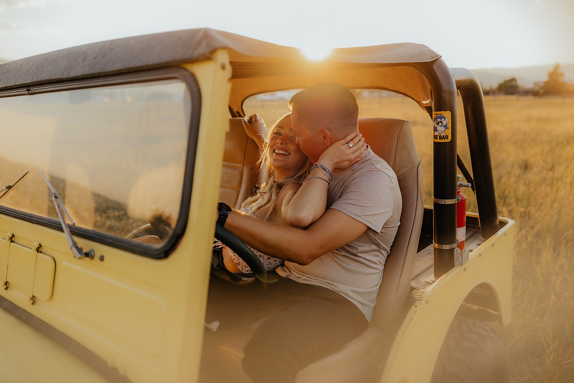 couple sit together in front seat of yellow jeep