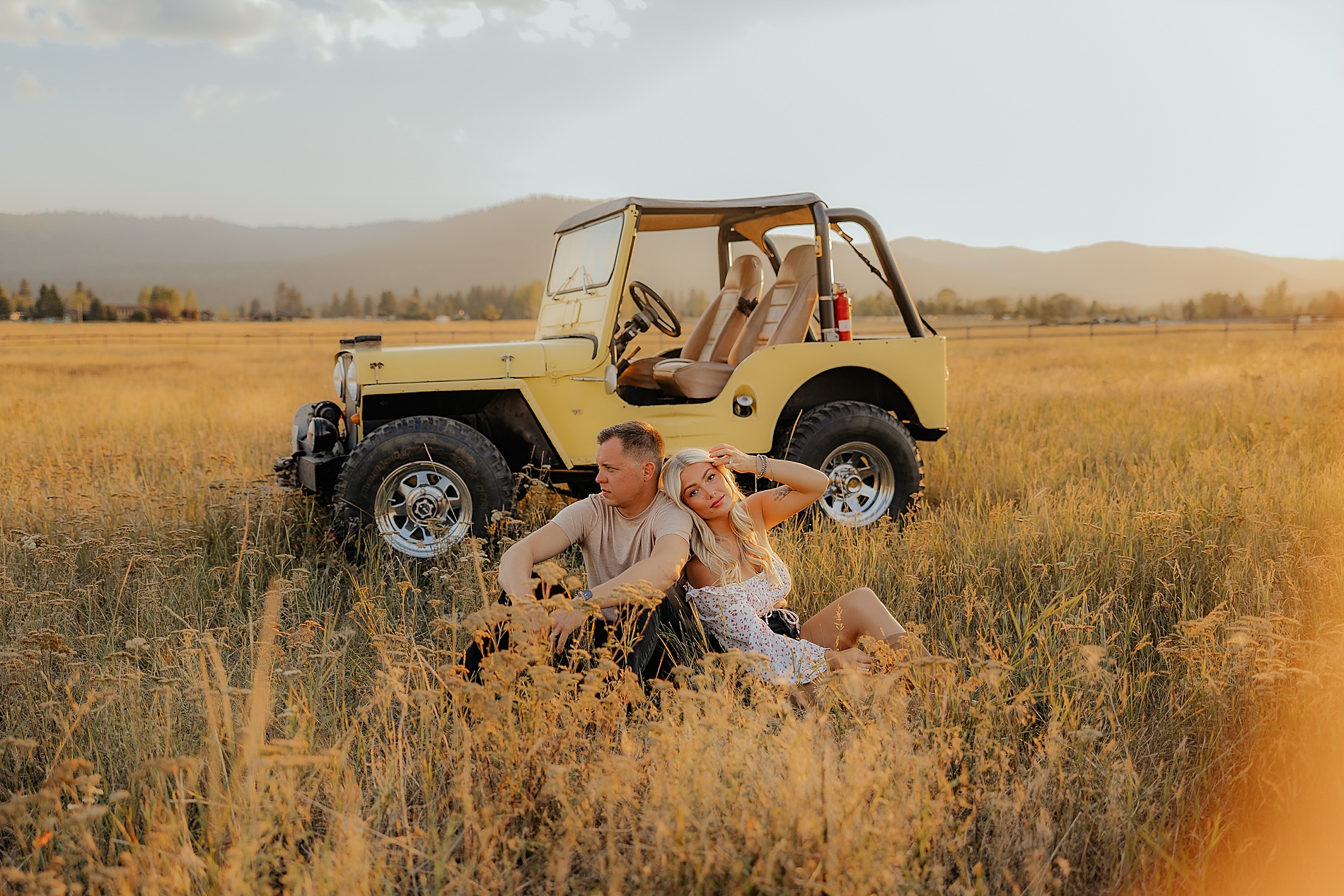 couple sit in field of tall golden grass in Montana 