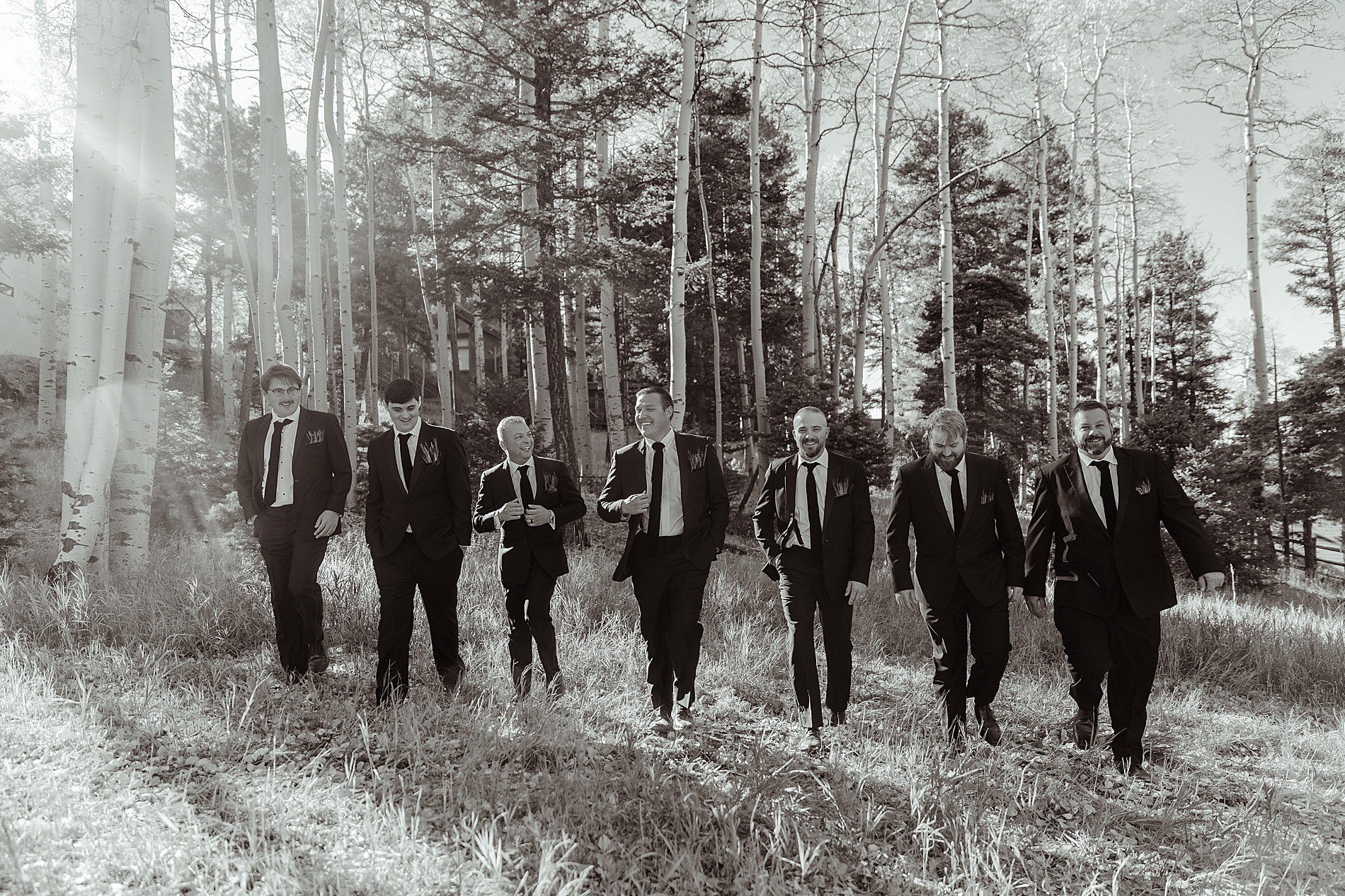 groom and groomsmen walk  through forest