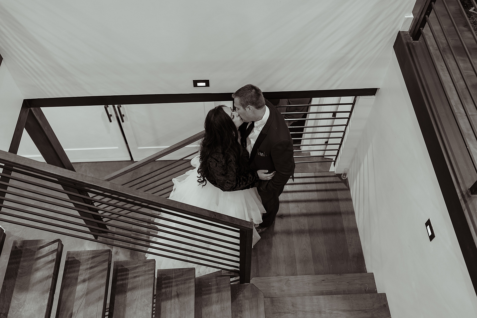 newlyweds kiss on landing of staircase 