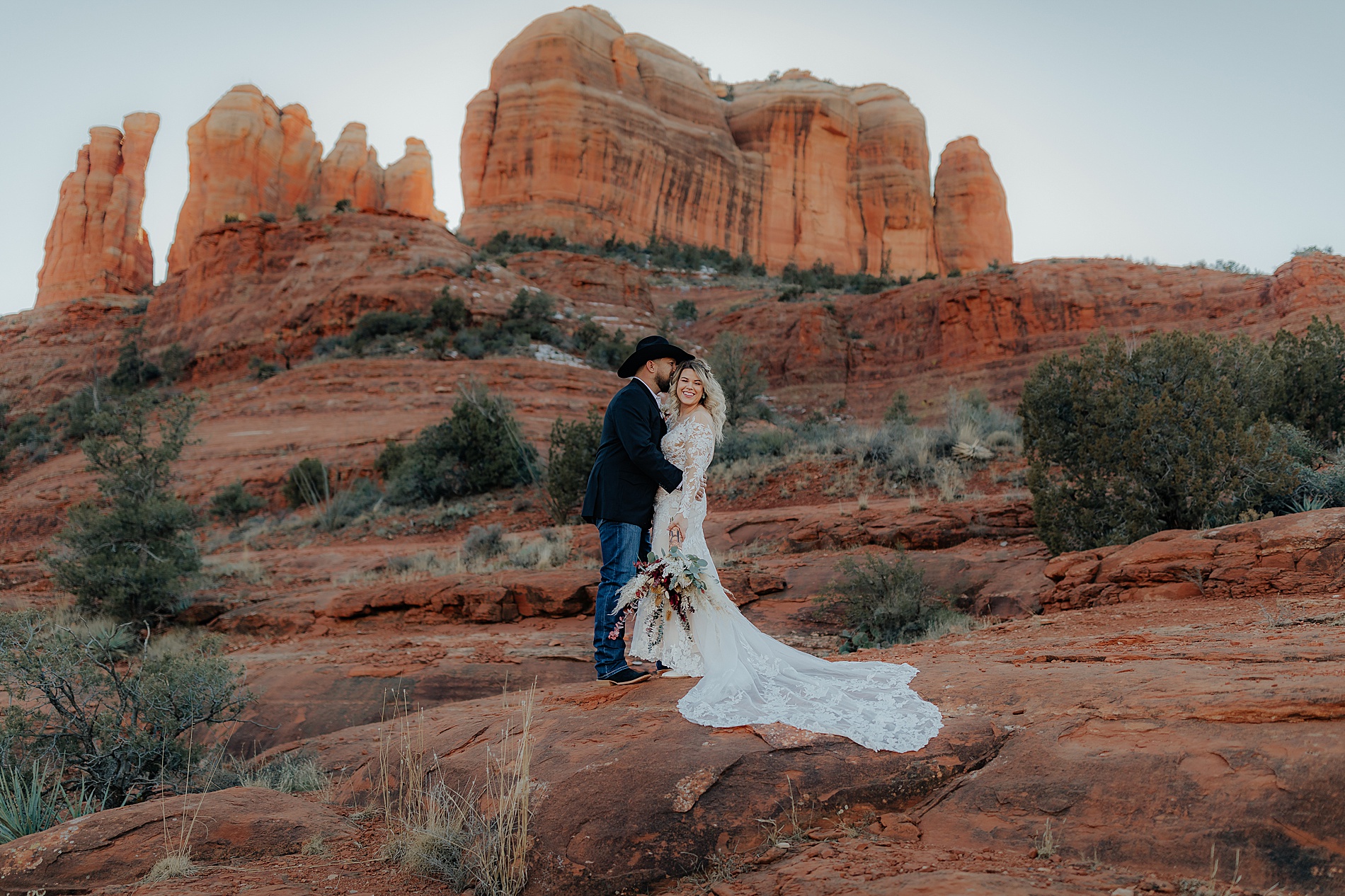 newlyweds kiss with beautiful rock formations in the background at Sedona AZ 