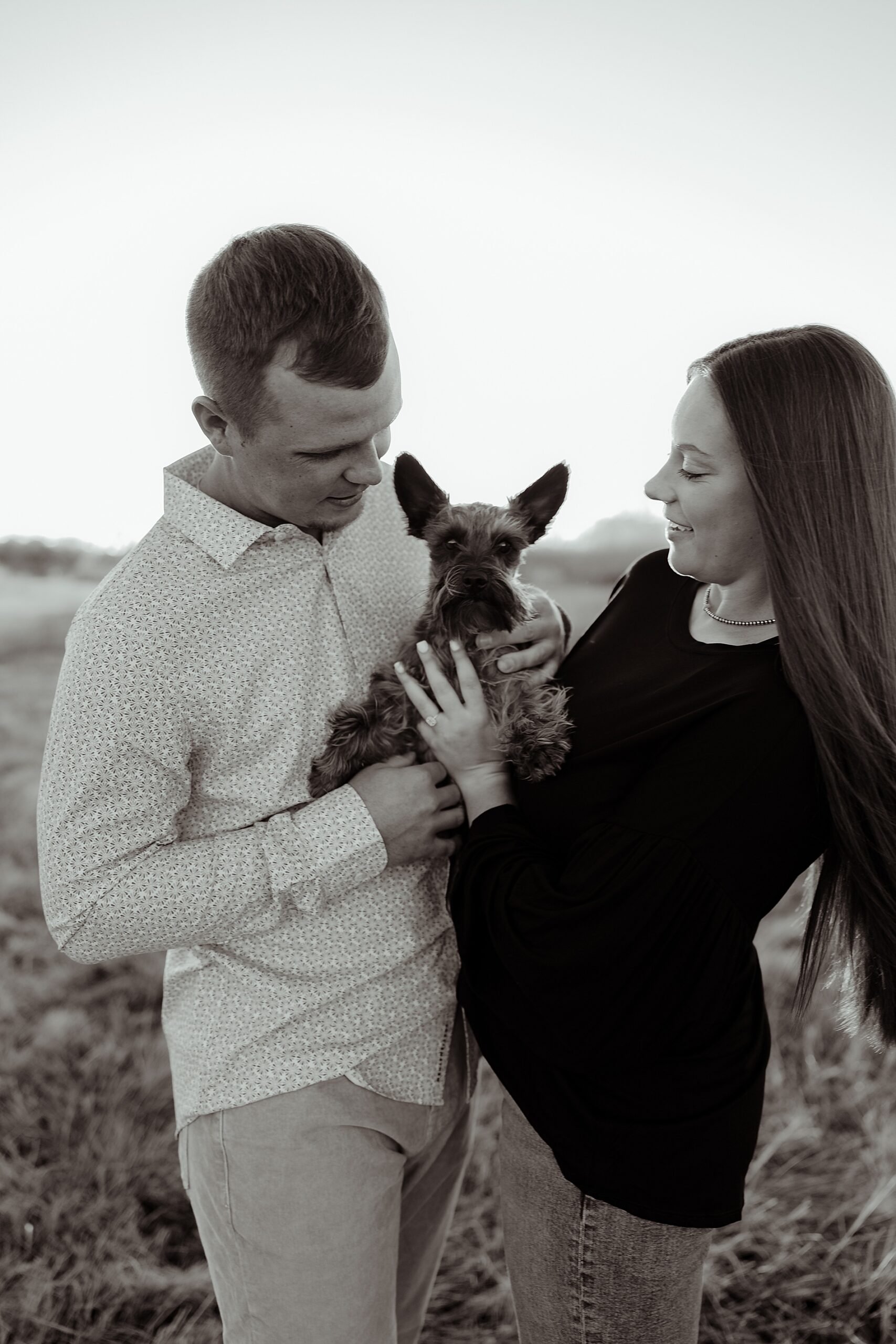 black and white engagement photo of couple holding their dog
