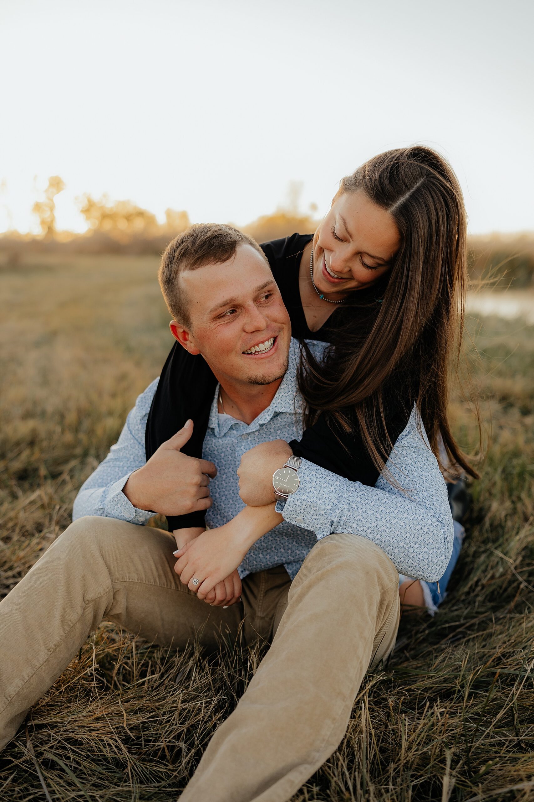 romantic engagement photo of woman hugging fiance as he sits on ground