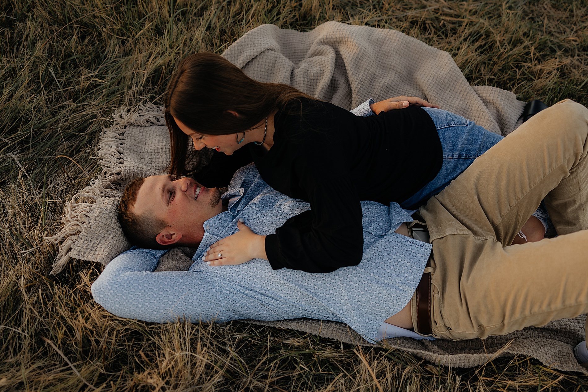 engaged couple lay together on grass