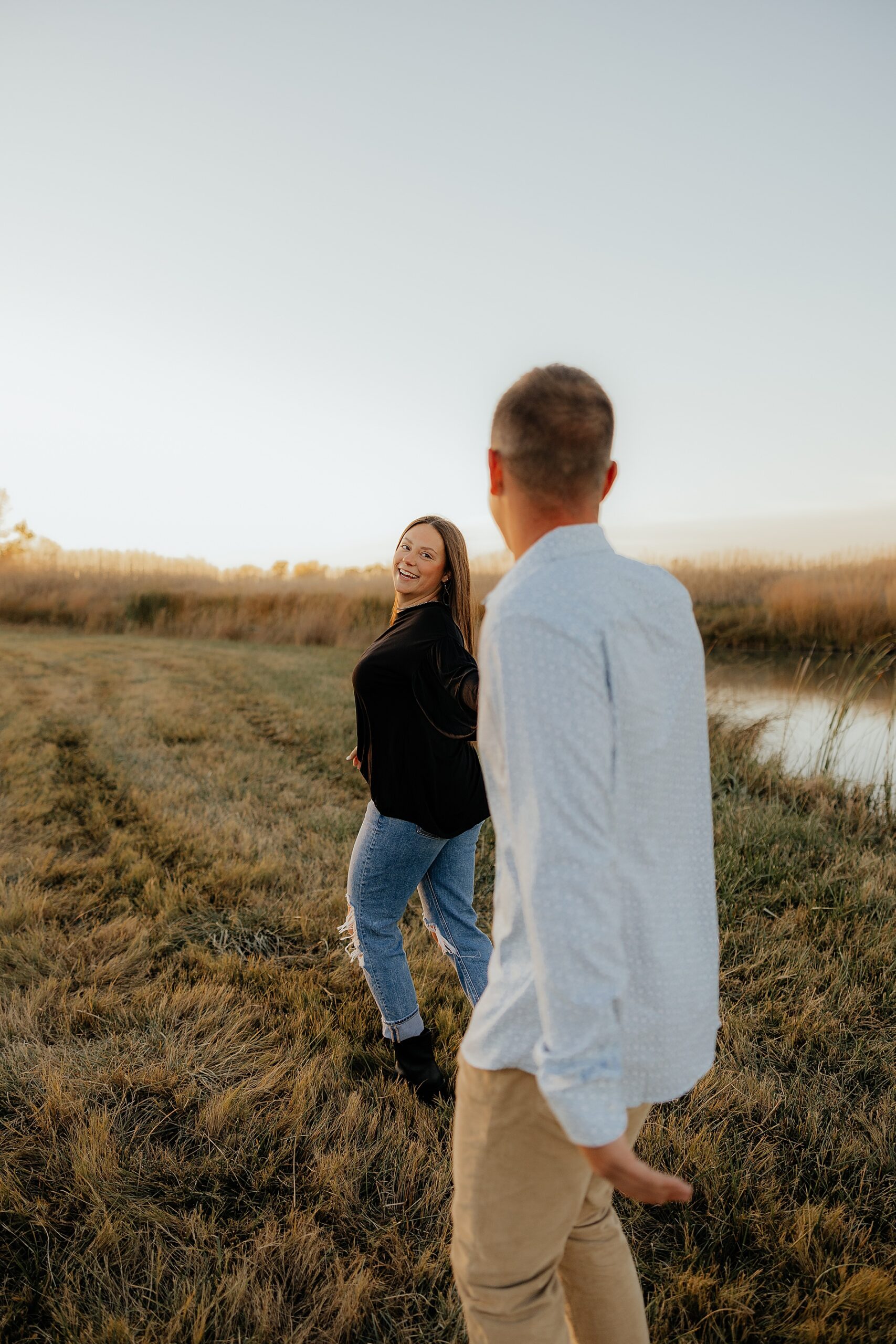 woman holding fiance's hand leads him as they walk