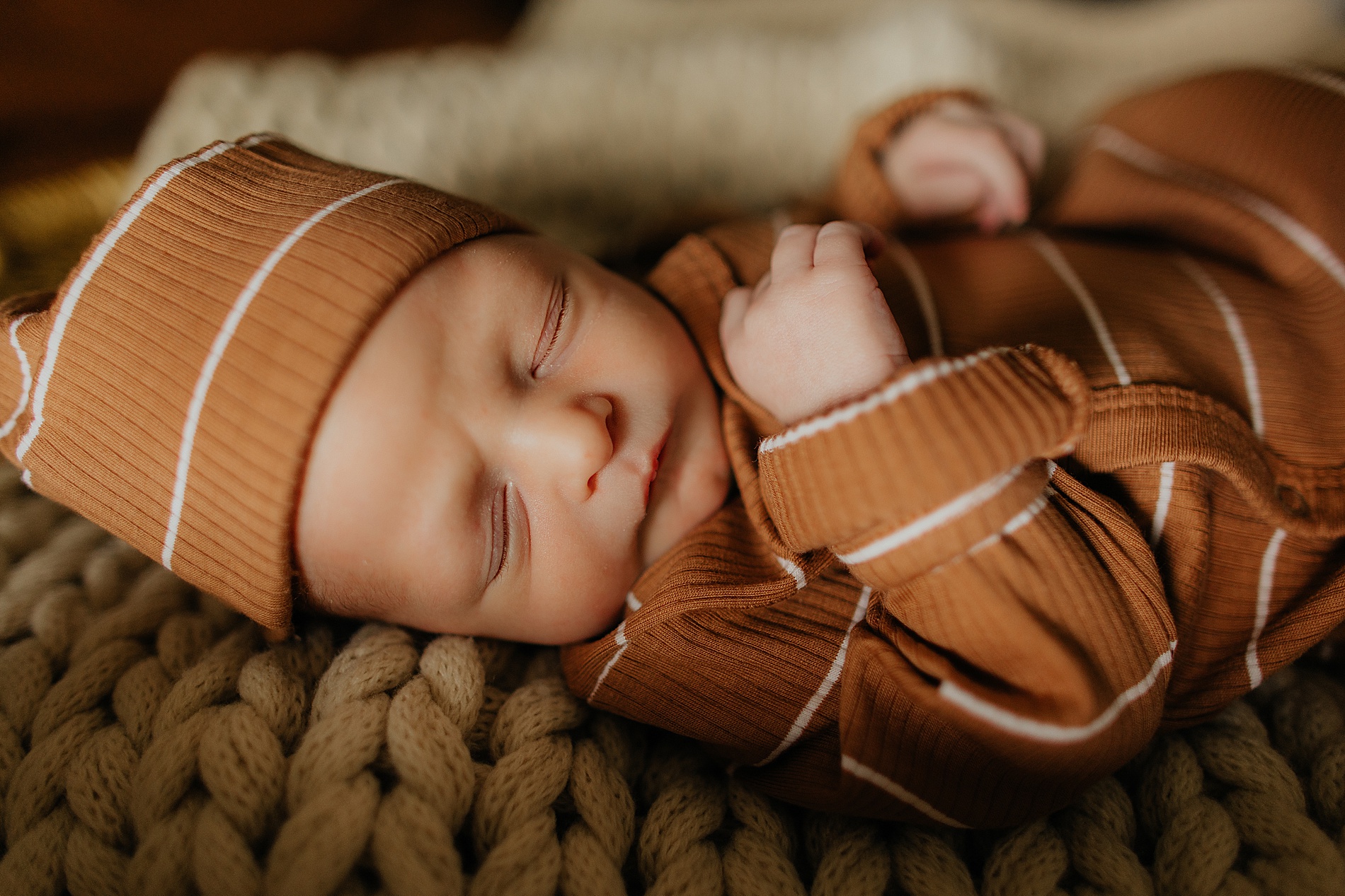 newborn in brown striped onesie and hat