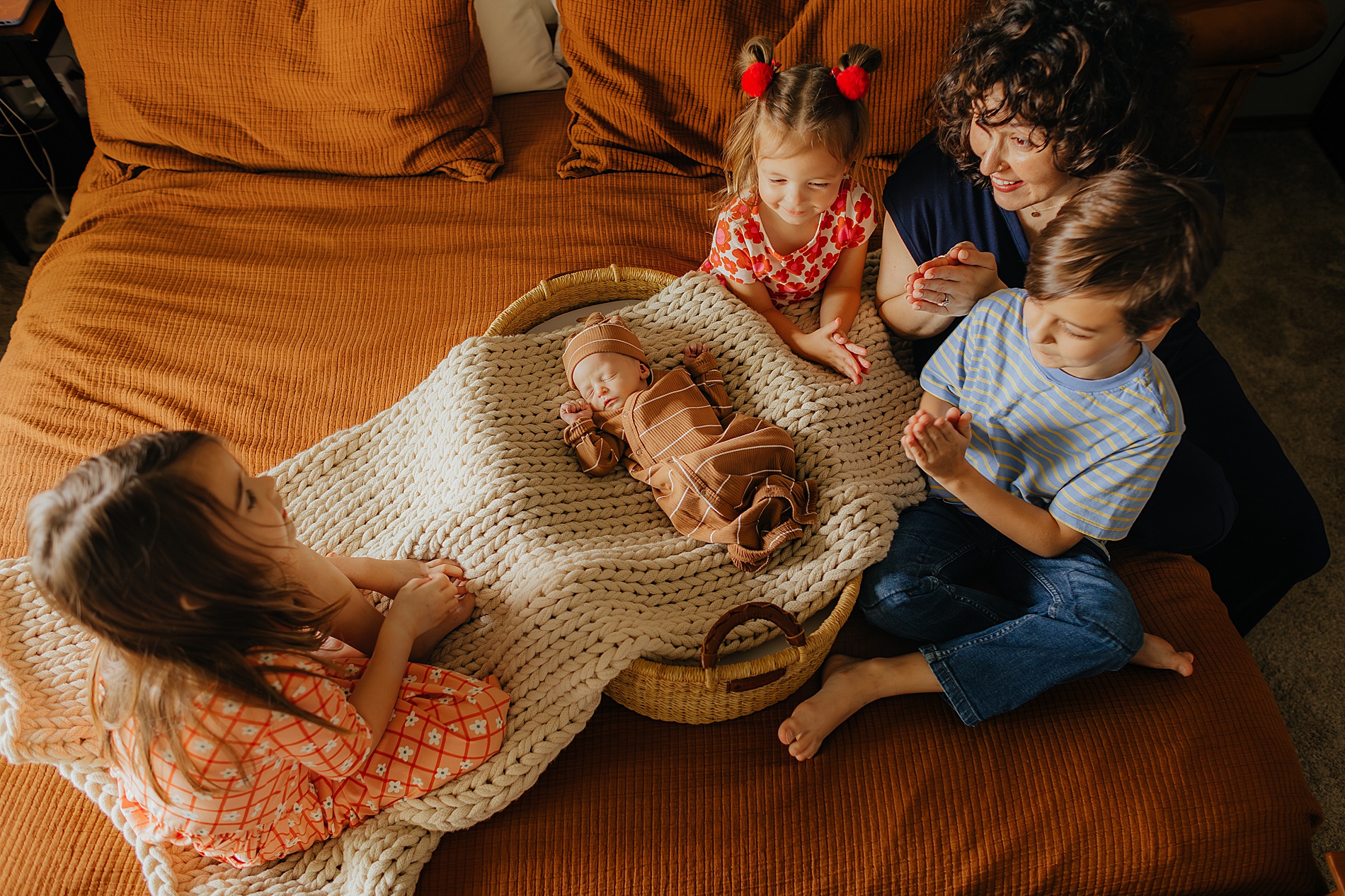 Mom and three siblings look at baby brother in bassinet