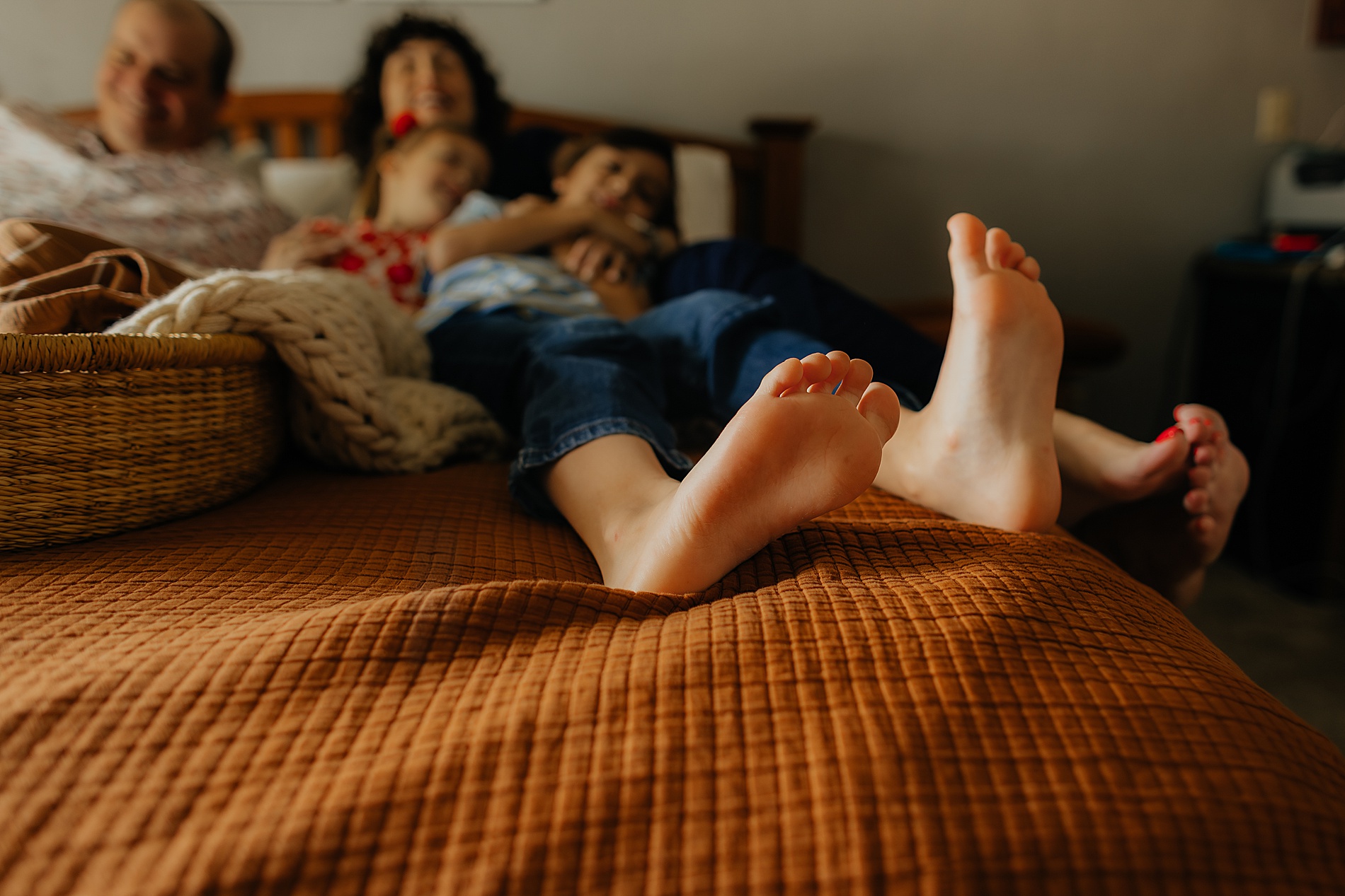 family snuggles on bed during in-home session