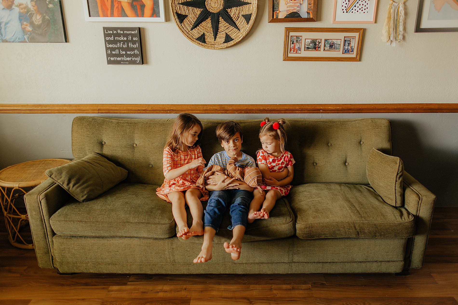 three older siblings hold baby brother while sitting on couch