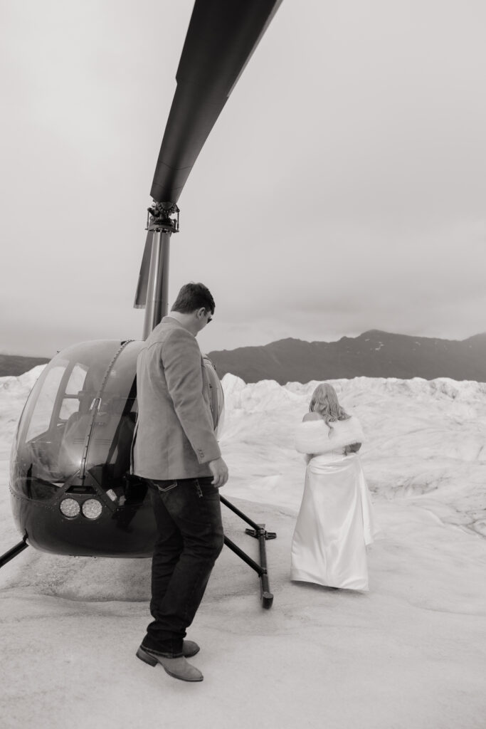 Bride and groom walking toward their helicopter on Knik Glacier after exploring the ice.