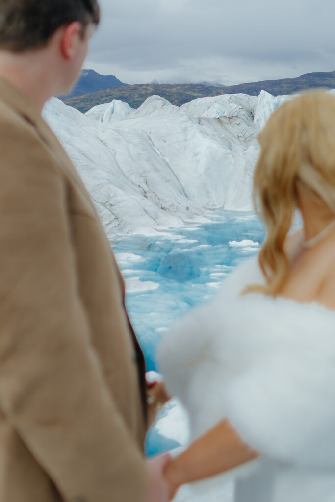 Bride and groom overlooking the blue ice and crevasses of Knik Glacier.