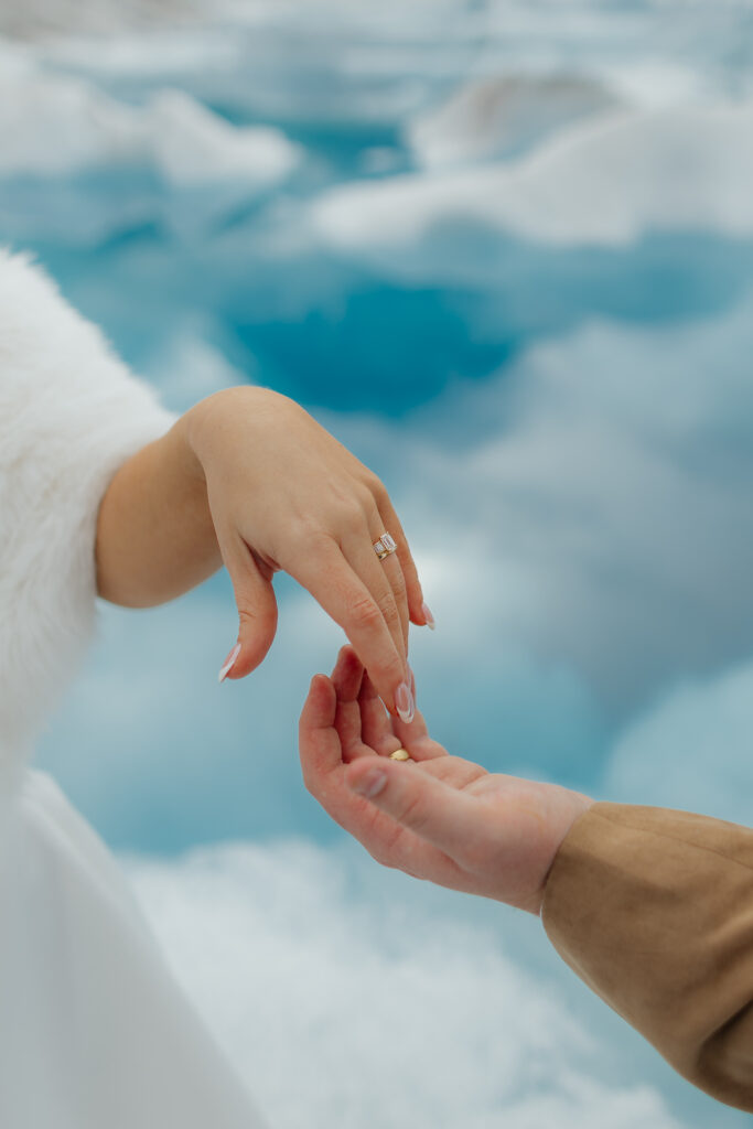 Close-up of the bride's wedding ring with blue glacial ice in the background.