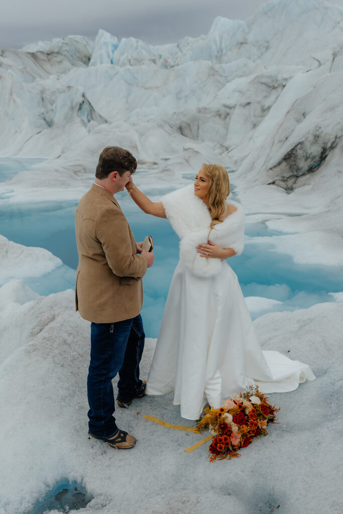 Bride and groom reading emotional private vows on Knik Glacier during their Alaska helicopter elopement.