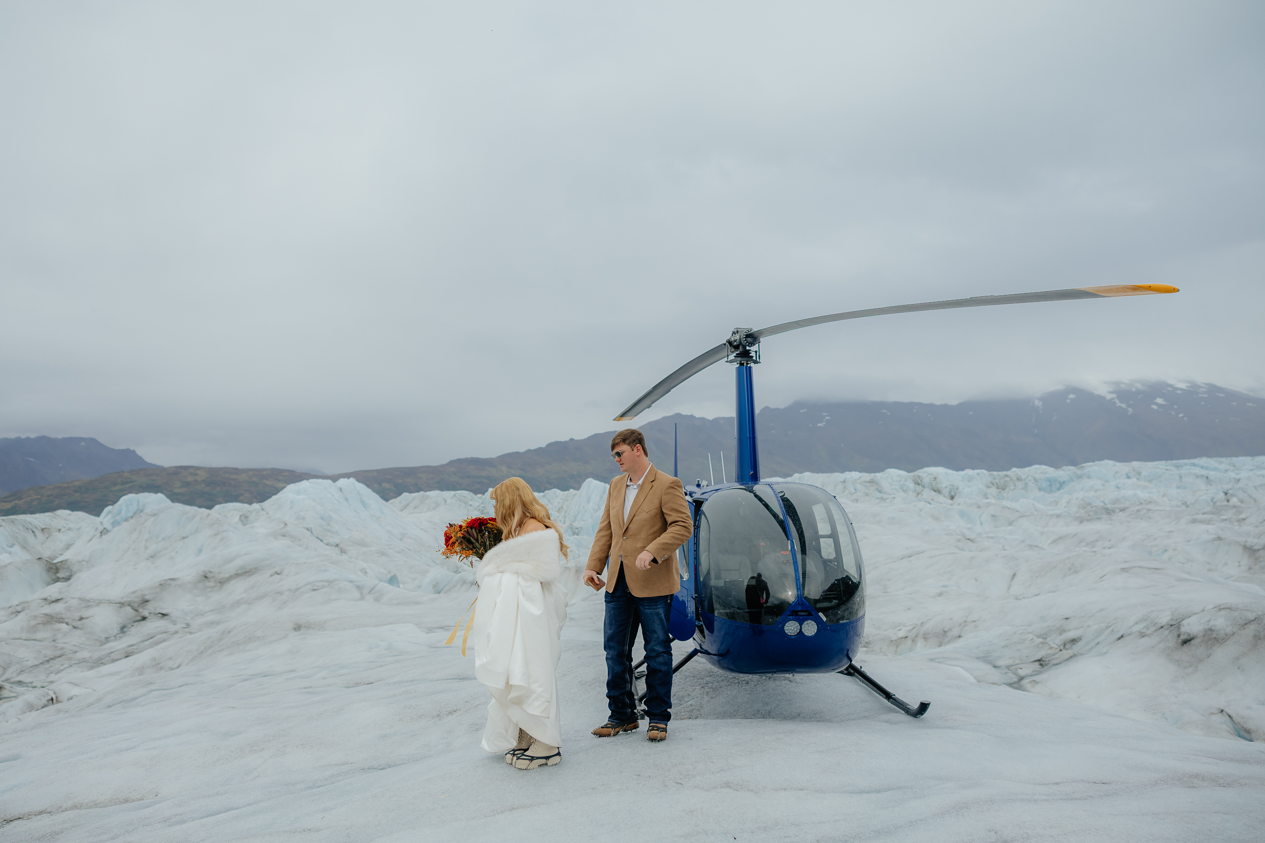 Bride and groom walking away from a helicopter on Knik Glacier during their Alaska helicopter elopement.