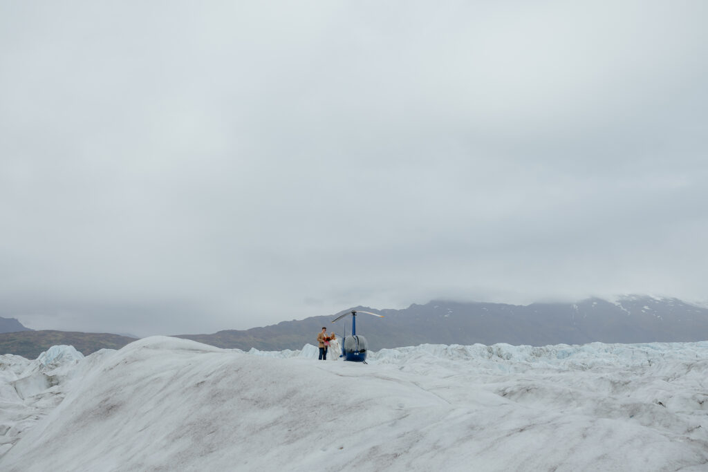 Bride and groom arriving on Knik Glacier after landing by helicopter in Alaska.