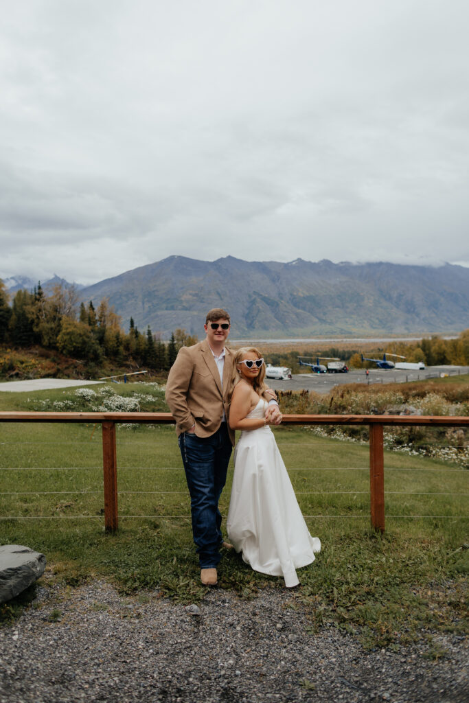 Bride and groom posing with mountain views before their Alaska helicopter wedding.