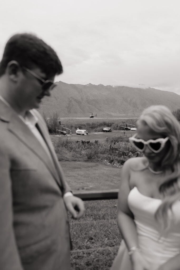 Bride and groom sharing a candid moment before boarding the helicopter in Alaska.