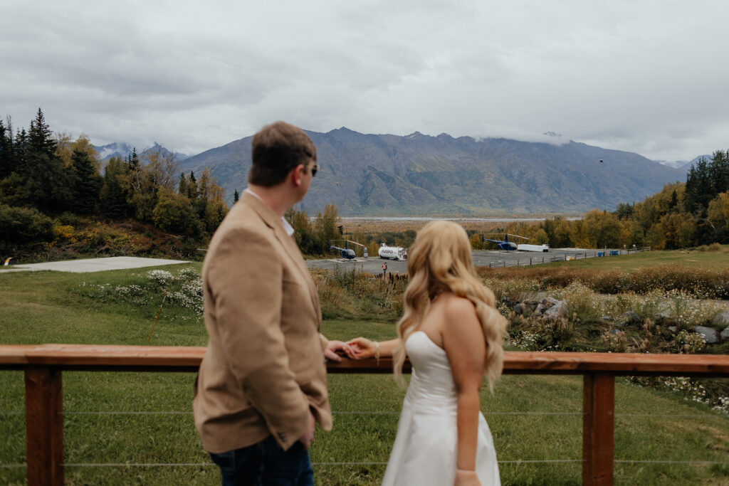Bride and groom taking in the mountain views before their helicopter flight in Alaska.