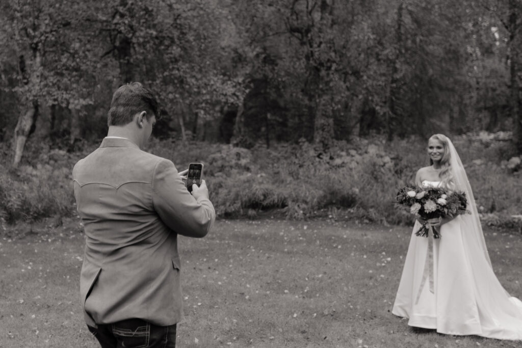 Groom taking a photo of his bride before their wedding in Alaska.