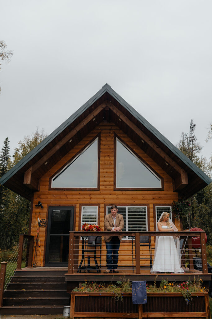 Bride and groom standing outside their cozy Alaska cabin before their Knik Glacier helicopter elopement.