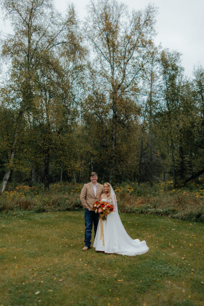 Bride and groom posing together outside their Alaska cabin