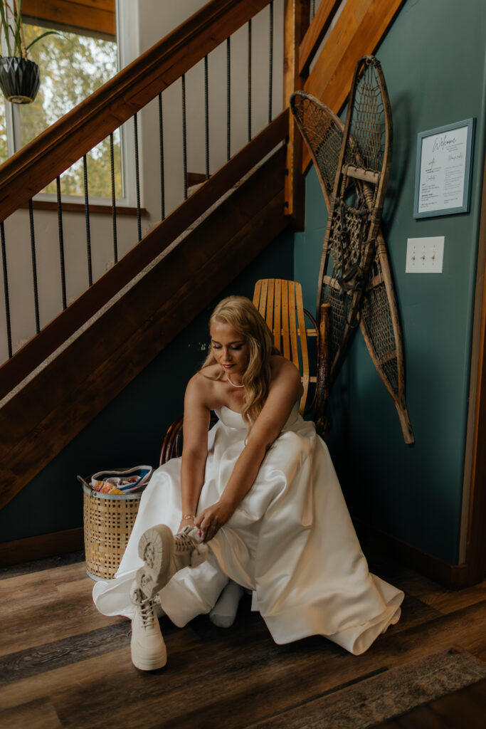 Bride lacing up white wedding boots before her Knik Glacier helicopter elopement.