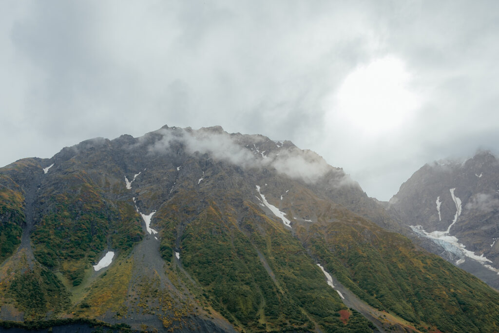 Rugged mountains surrounding Knik Glacier on an overcast day in Alaska.